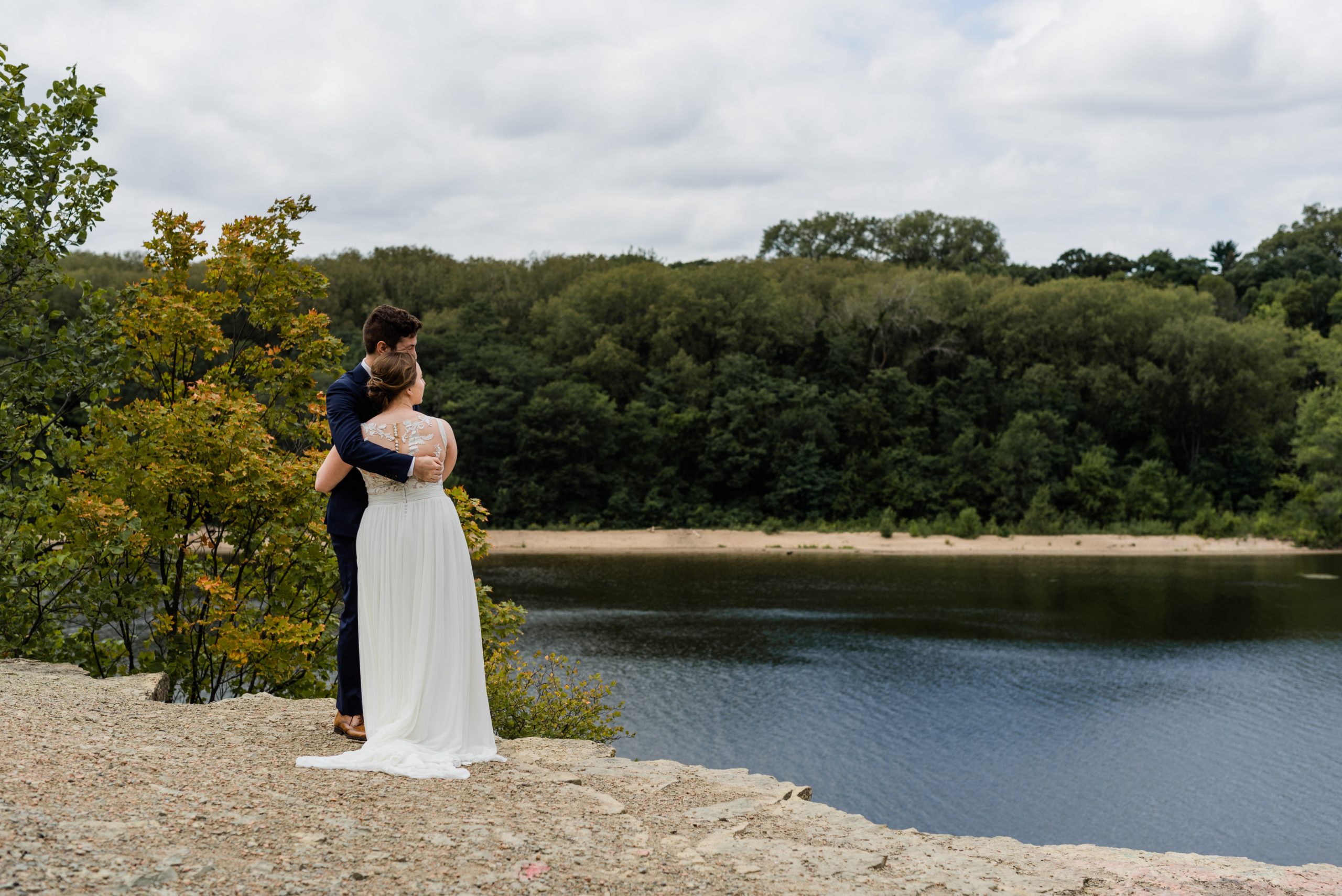 Bride and groom hugging and looking at the Mississippi River in St. Paul.