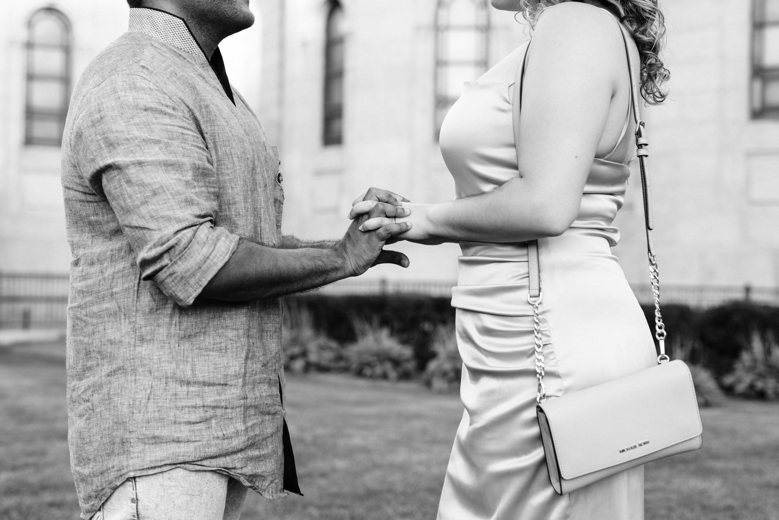 Couple standing holding hands while looking at each other.