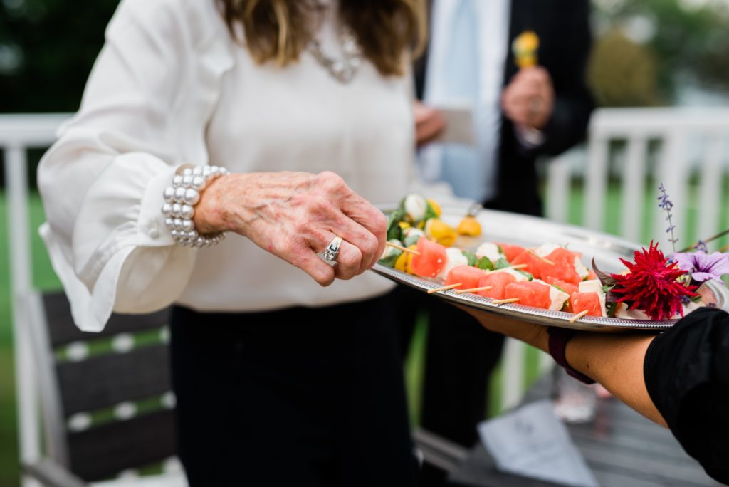 Woman grabbing food from tray at cocktail hour.