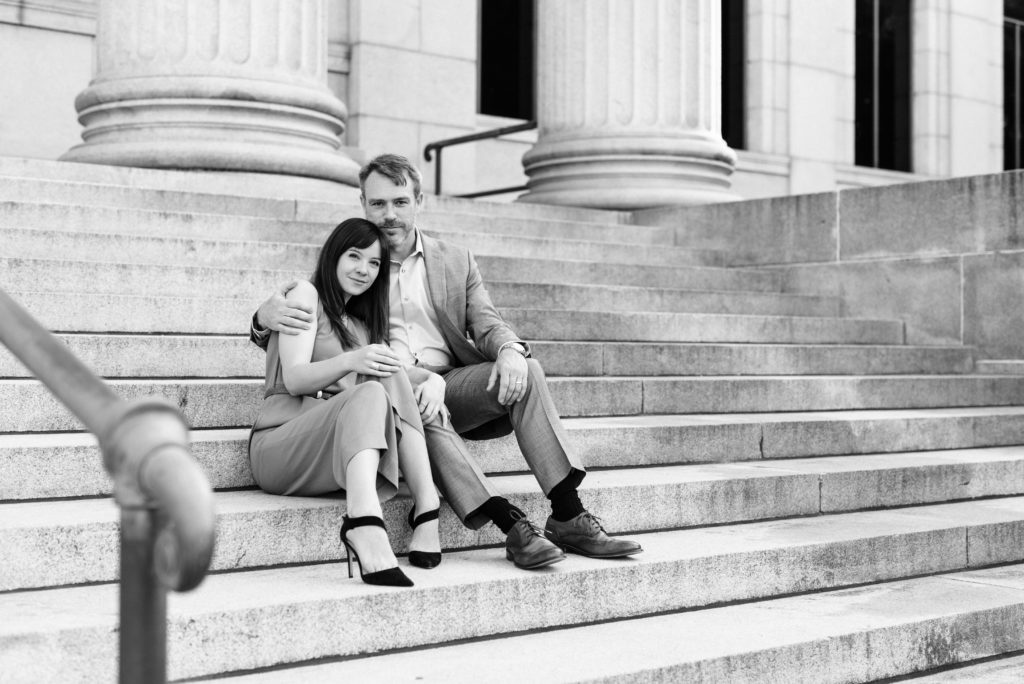 Couple sitting on steps looking at the camera seriously.