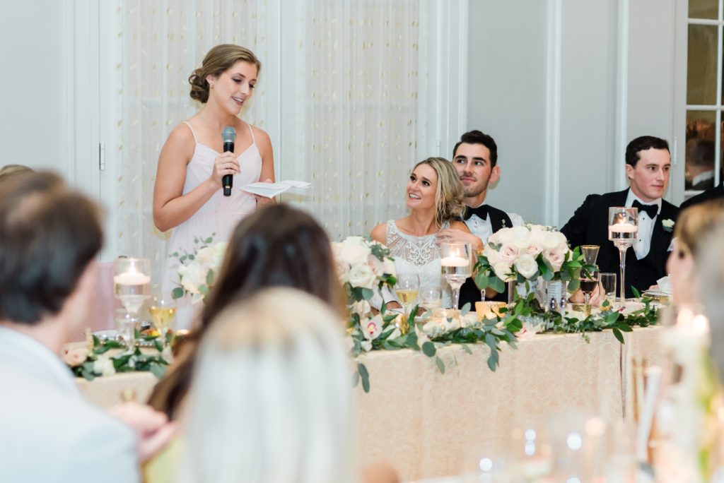 Maid of honor giving speech while bride and groom look on.
