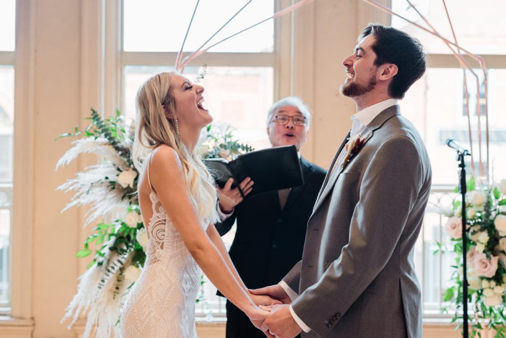 Wedding couple laughing together during ceremony.