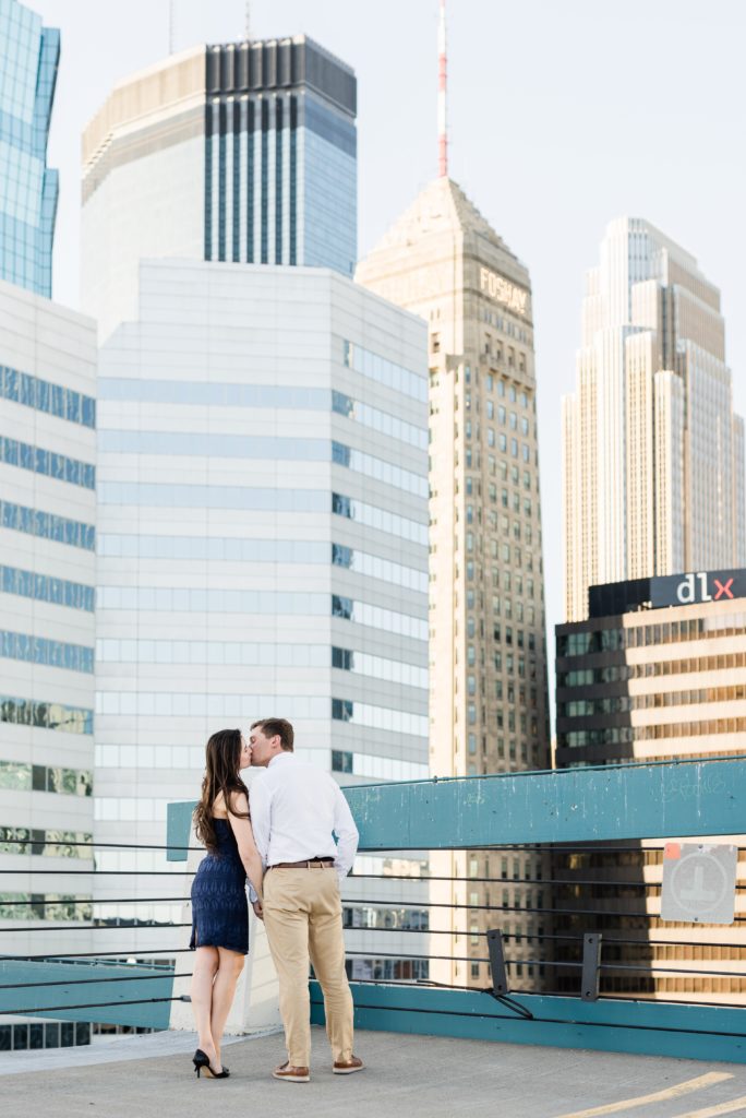Couple kissing on parking ramp with a view of Minneapolis.