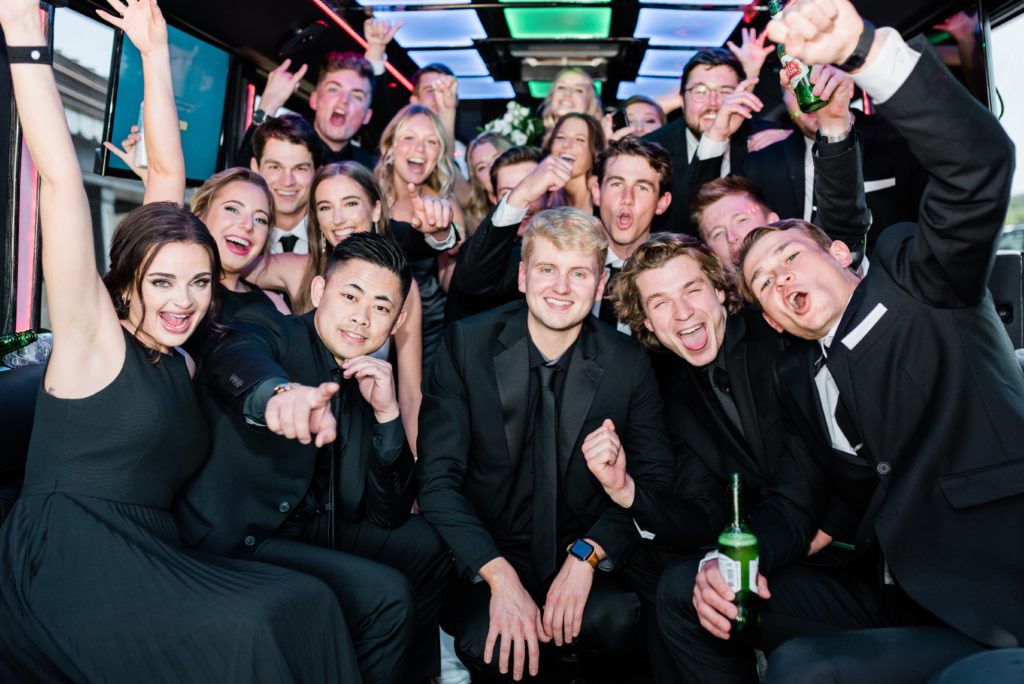 Wedding party group cheering on a party bus.