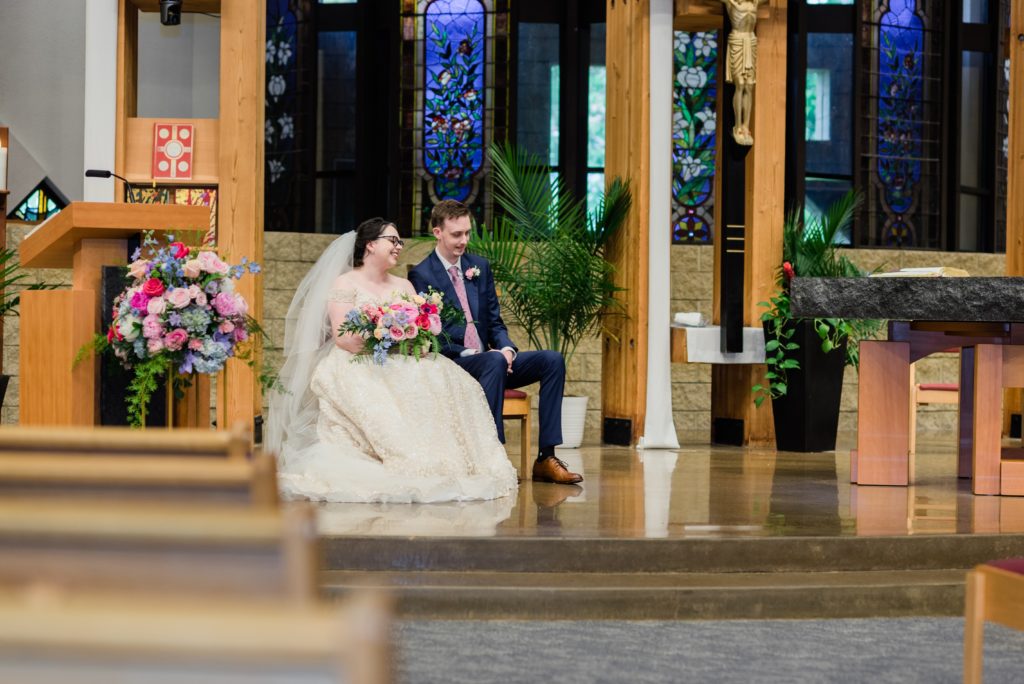 Bride and groom laughing at the altar during Catholic ceremony. 
