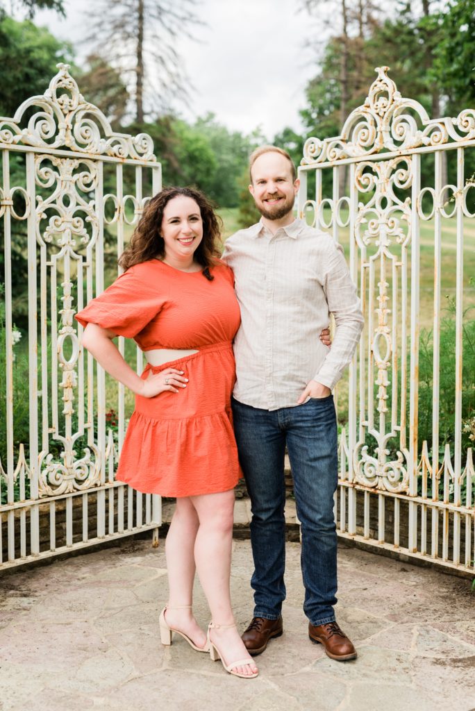 Husband and wife smiling in front of a gate.