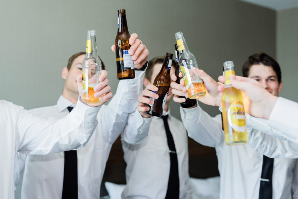 The groomsmen cheering with bottles of beer.