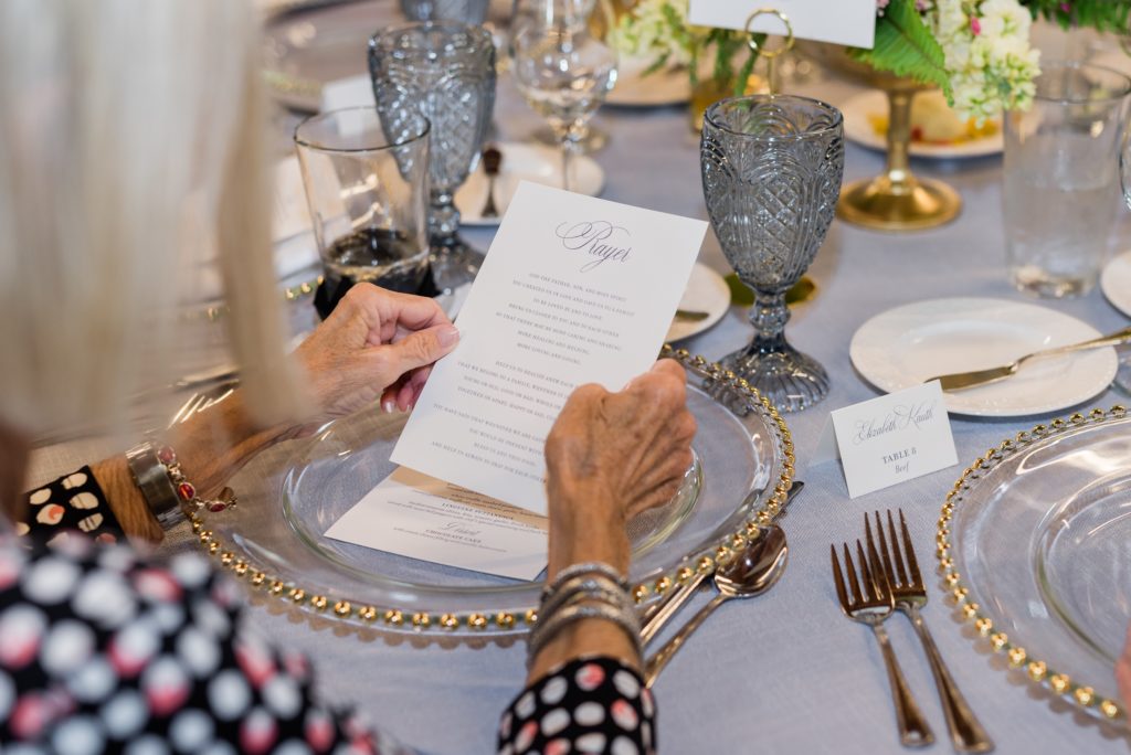 A wedding guest holding onto a prayer card at the table.