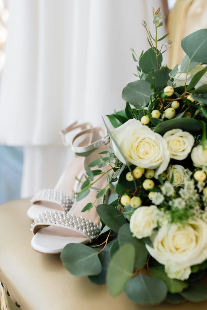 Bridal high heels, flowers, and wedding dress in background | Bavaria Downs Wedding Photography by Gretchen Yell