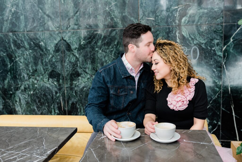 Boyfriend kisses girlfriend's forehead while on a coffee date.