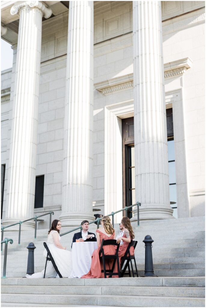 Bride and groom and guests sit outside the Minneapolis Institute of Art during cocktail hour.