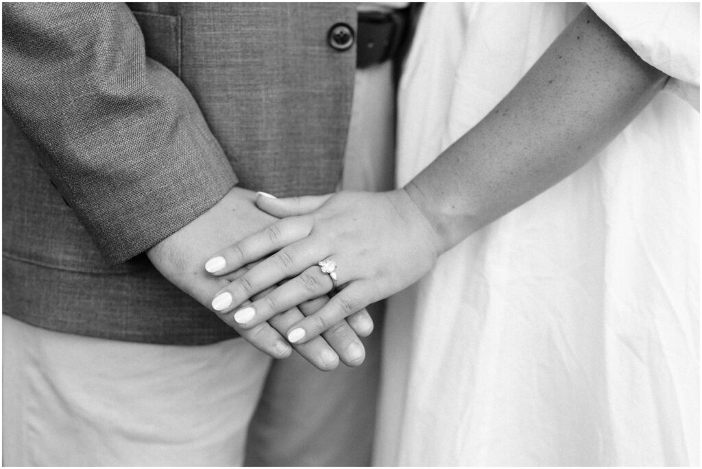 Engaged couple with layered hands showing engagement ring.