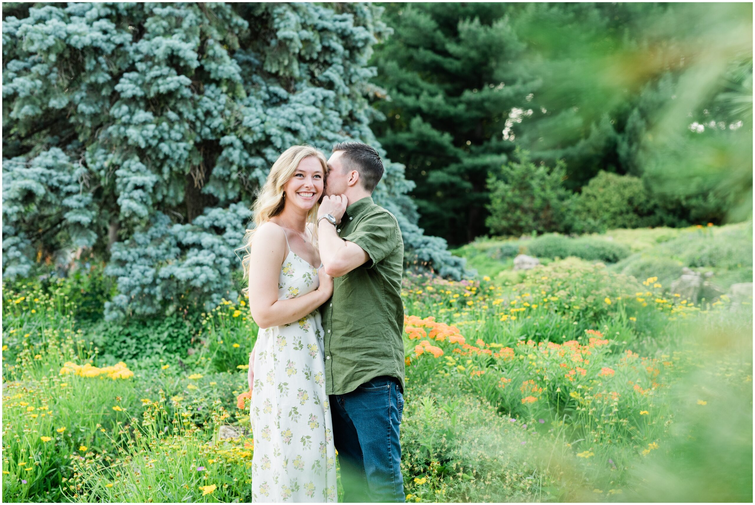 Couple smiling and whispering in a garden.