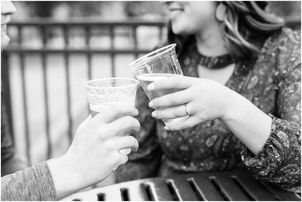 Couple clink beer glasses while outside.