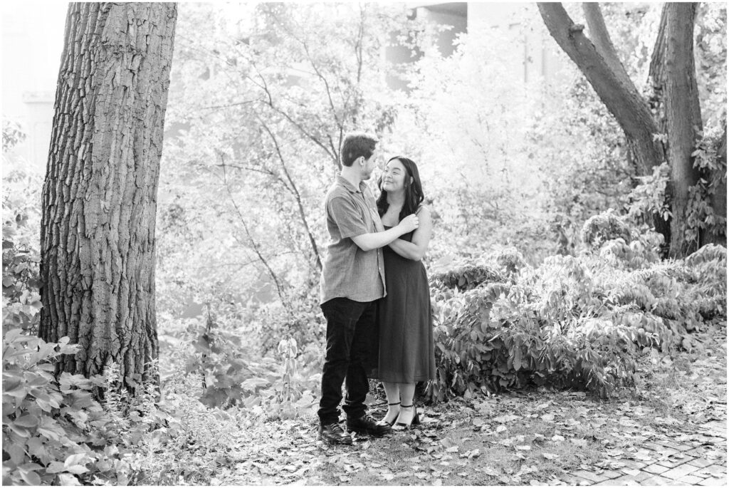 Couple look at each other while hugging in nature.