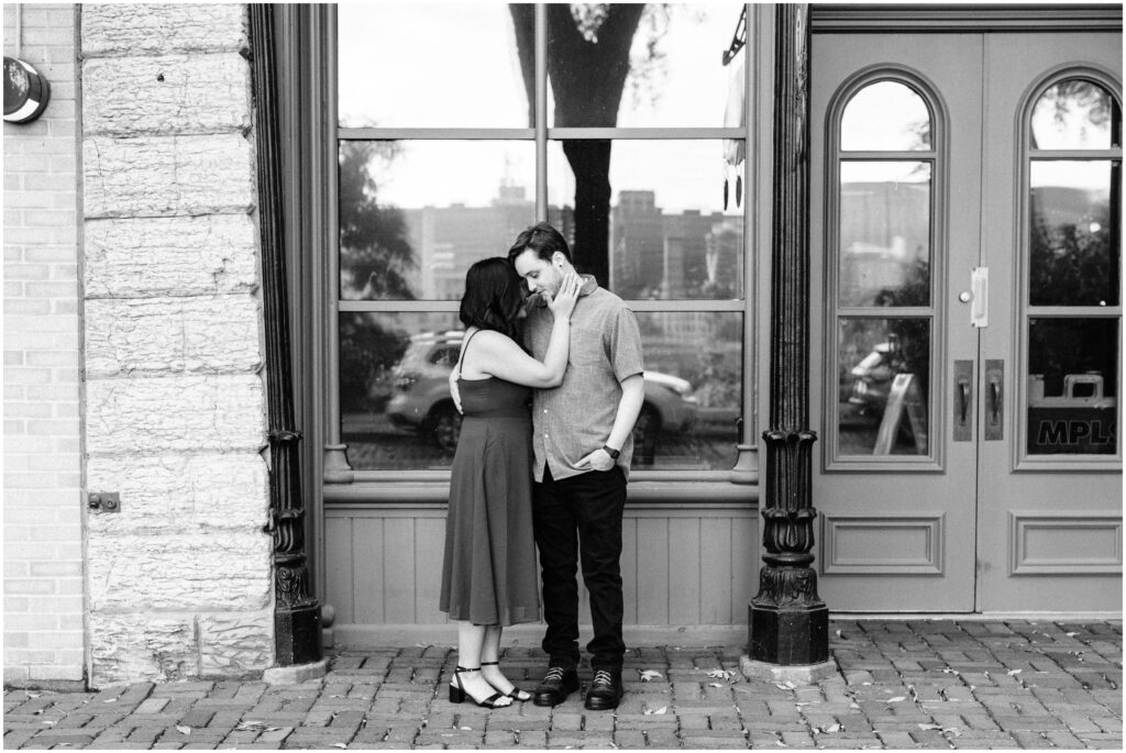 Boyfriend and girlfriend hug in front of old building.