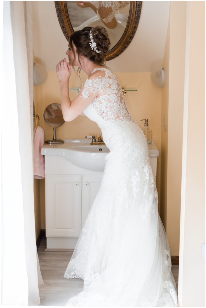 Bride getting ready while looking at a mirror at James Mulvey Inn.
