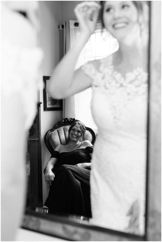 Mother of the Bride smiling at the bride through a mirror.
