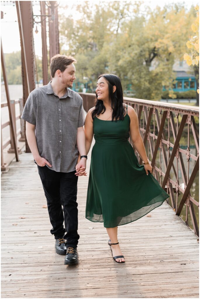 Couple is walking holding hands on Merriam bridge in Minneapolis.