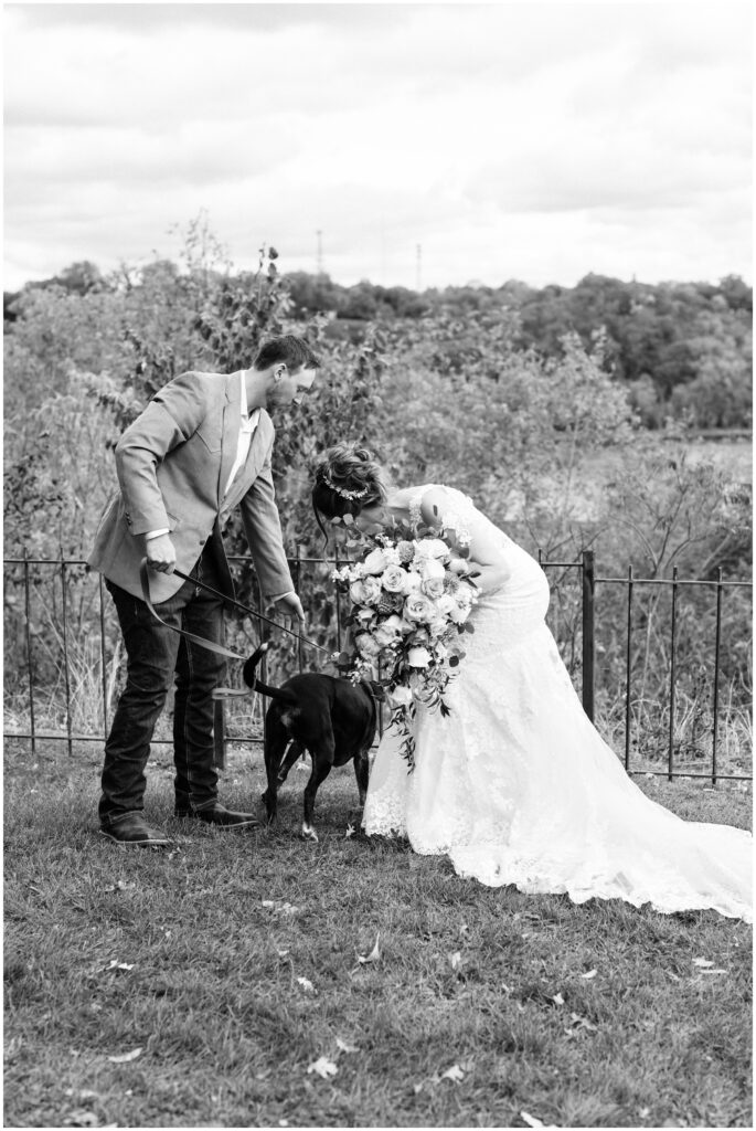 Bride and groom petting their dog.