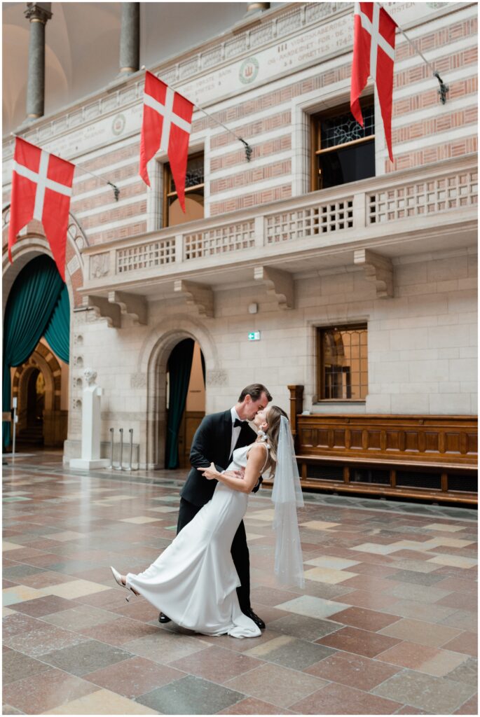 Bride and groom kiss inside the Copenhagen City Hall.