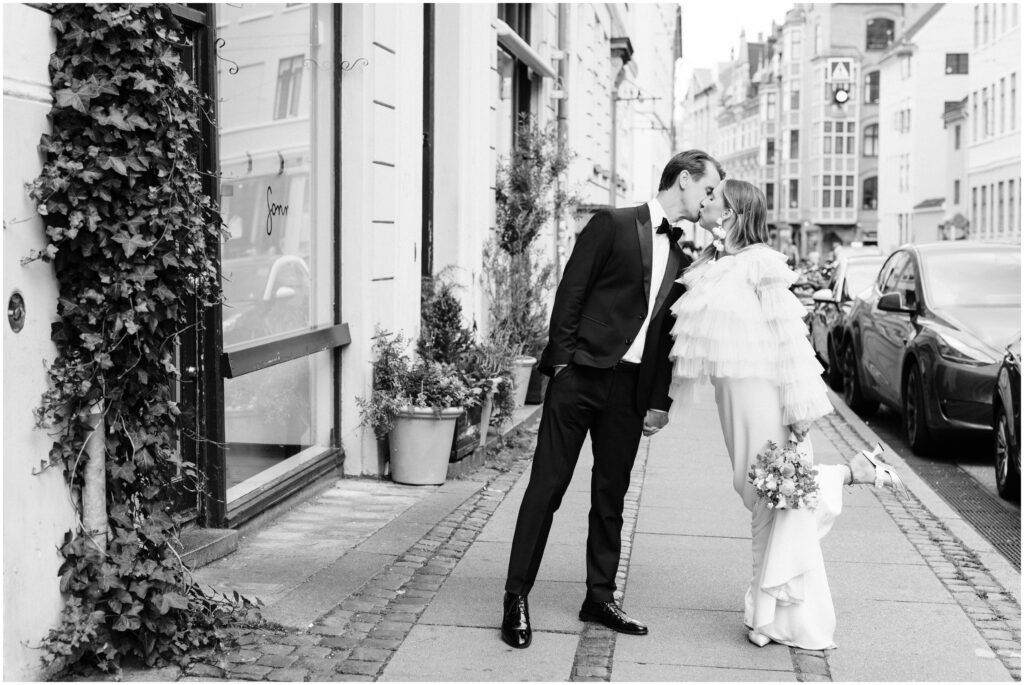The bride and groom share a kiss on the city streets during their Copenhagen Elopement. 