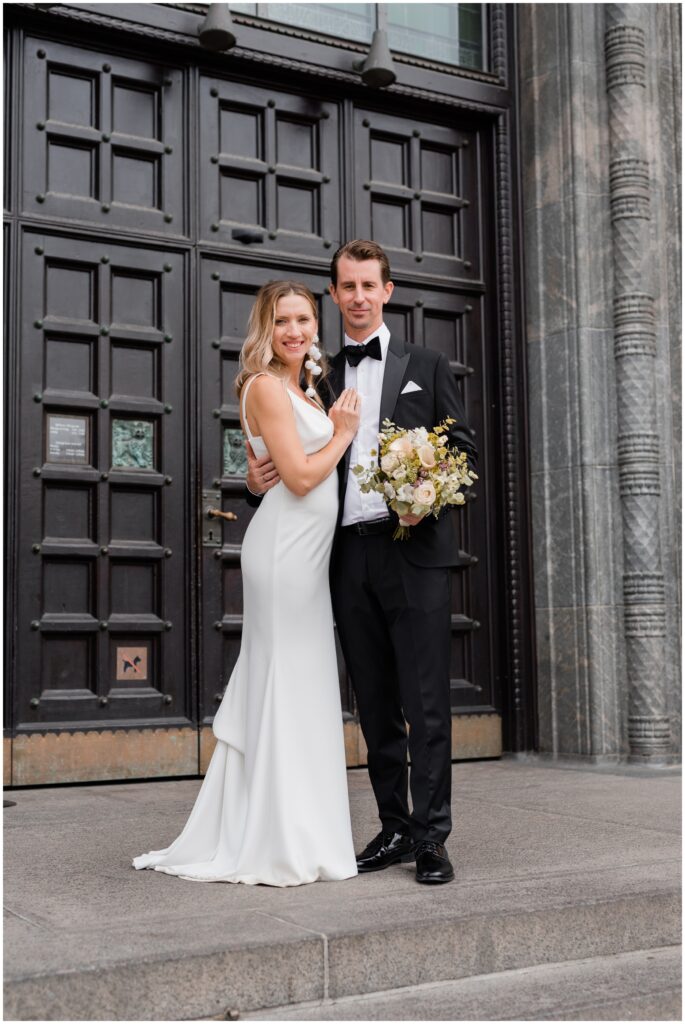 Bride and groom pose in front of the Copenhagen City Hall.