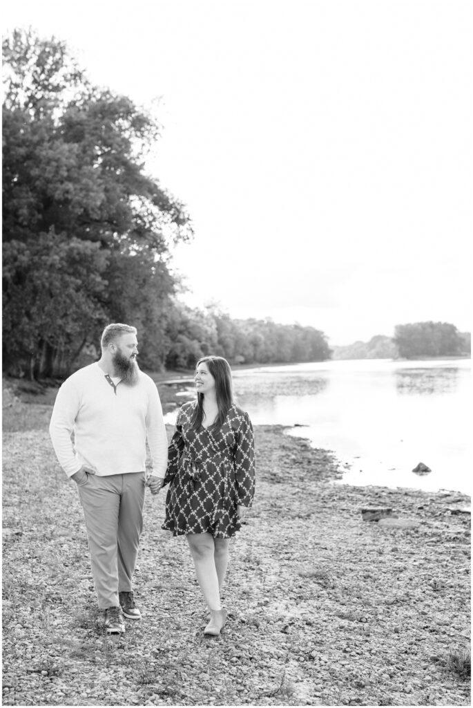 Engaged couple walk along the Mississippi River. 
