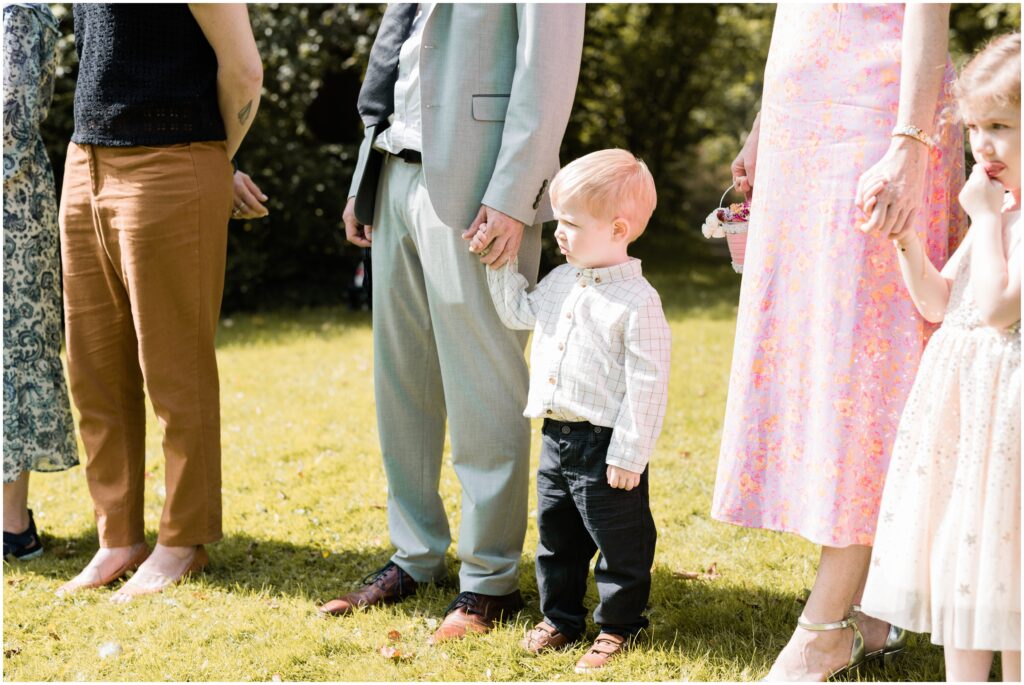 Small boy watching the wedding ceremony holding his dad's hand. 