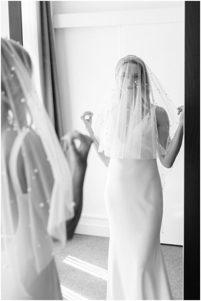 The bride looking at herself in the mirror with the veil over her face at Scandic Palace Hotel, Copenhagen, Denmark. 