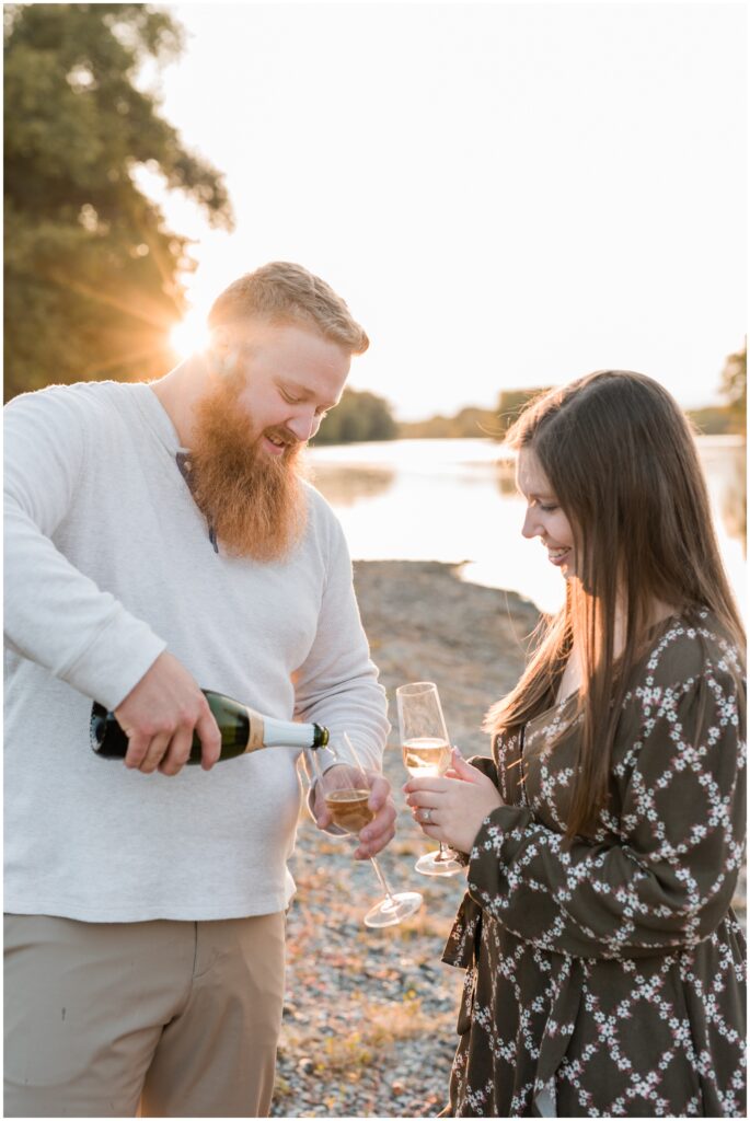 Boyfriend pours girlfriend champagne to drink at the Mississippi River. 