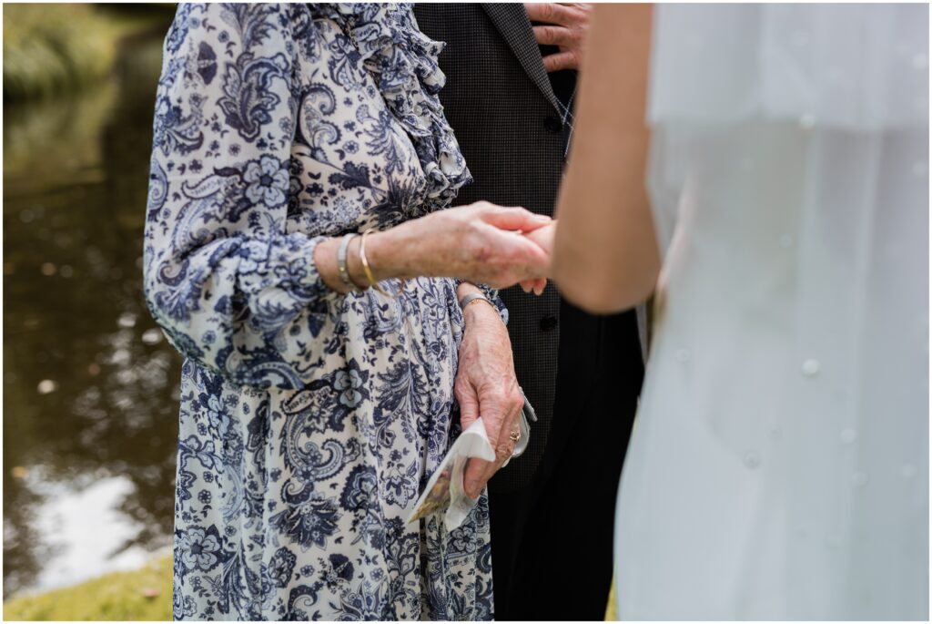 The Mother of the Groom holds the bride's hand.
