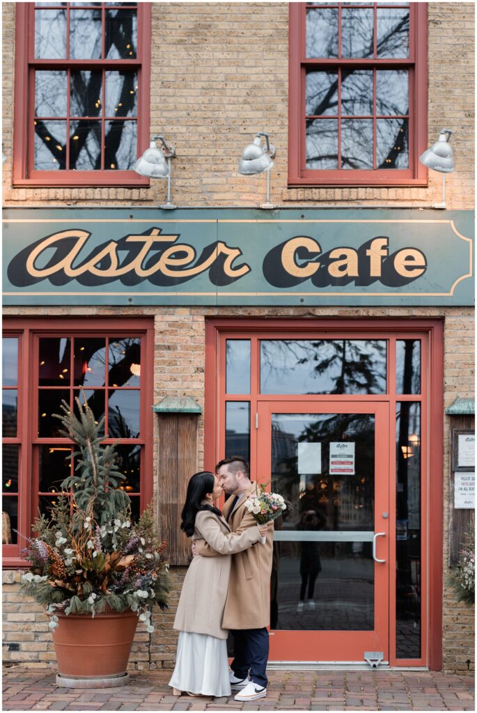 A couple kiss in front of Aster Cafe.