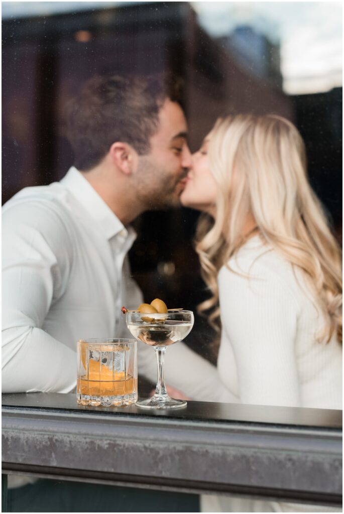 A couple kiss with their holiday drinks at Tulibee Restaurant at the Hewing Hotel in Minneapolis, MN. 
