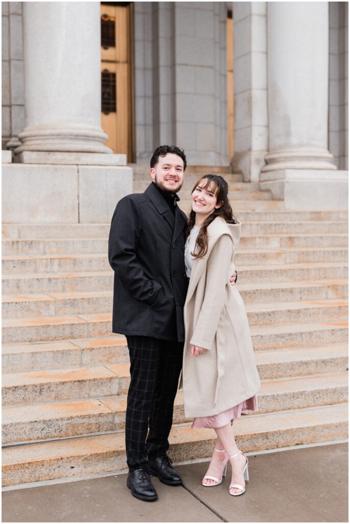 A couple poses outside the Basilica of Saint Mary in pea-coats. 